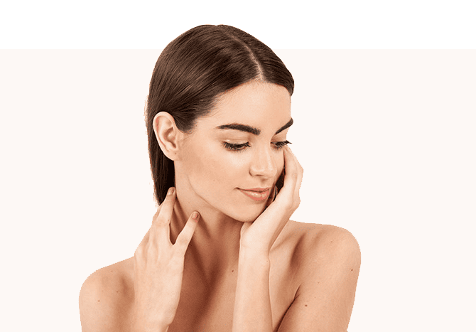 A Woman With Long, Dark Hair Gently Touches Her Face And Neck With Her Hands. She Has A Calm Expression And Is Looking Downward, Set Against A Soft Peach Colored Background.